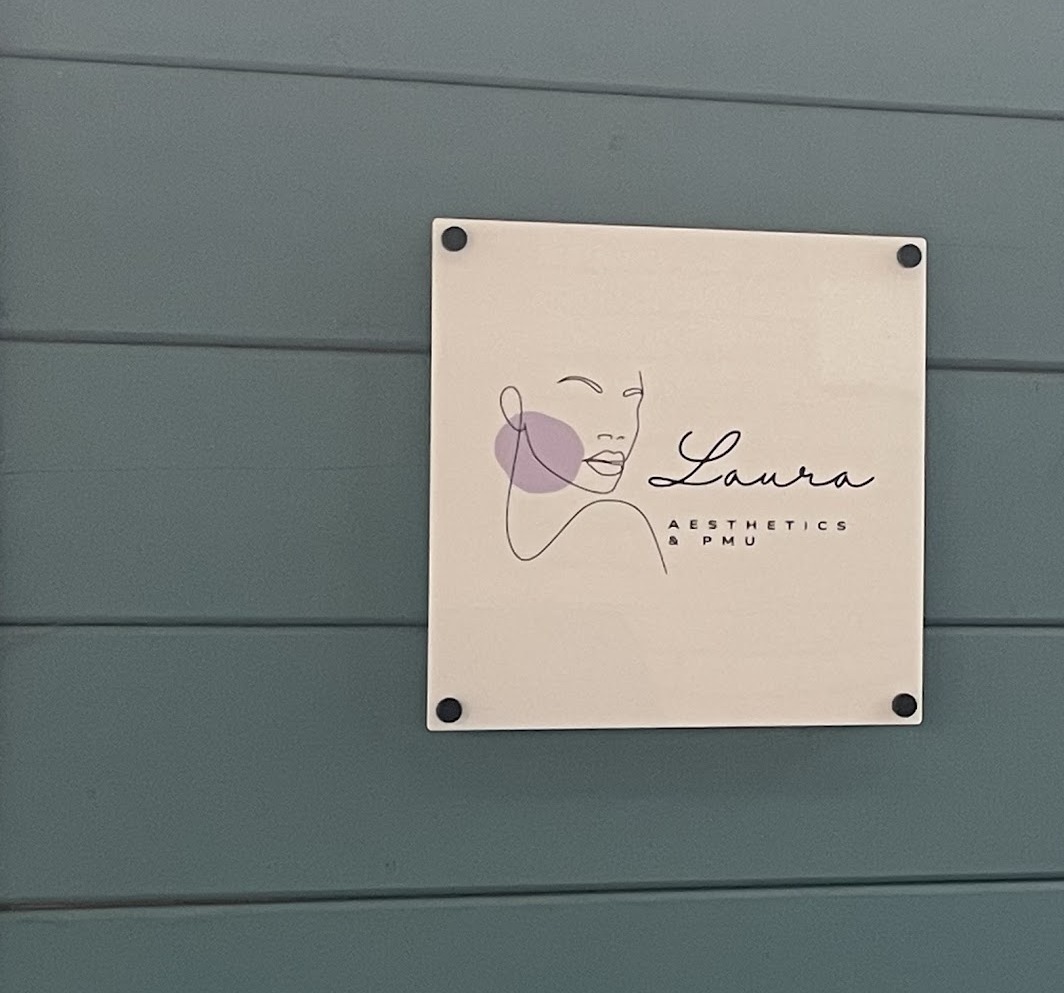 The Laura Aesthetics and PMU sign on the sage green cabin wall